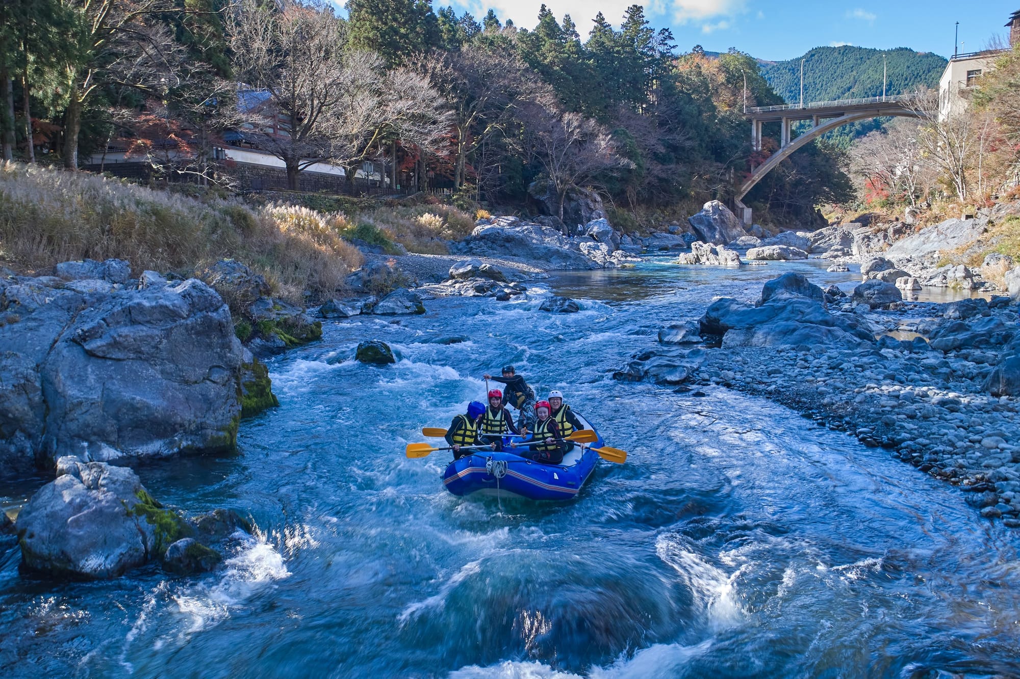 Una embarcación de rafting desciende un río entre rocas y árboles