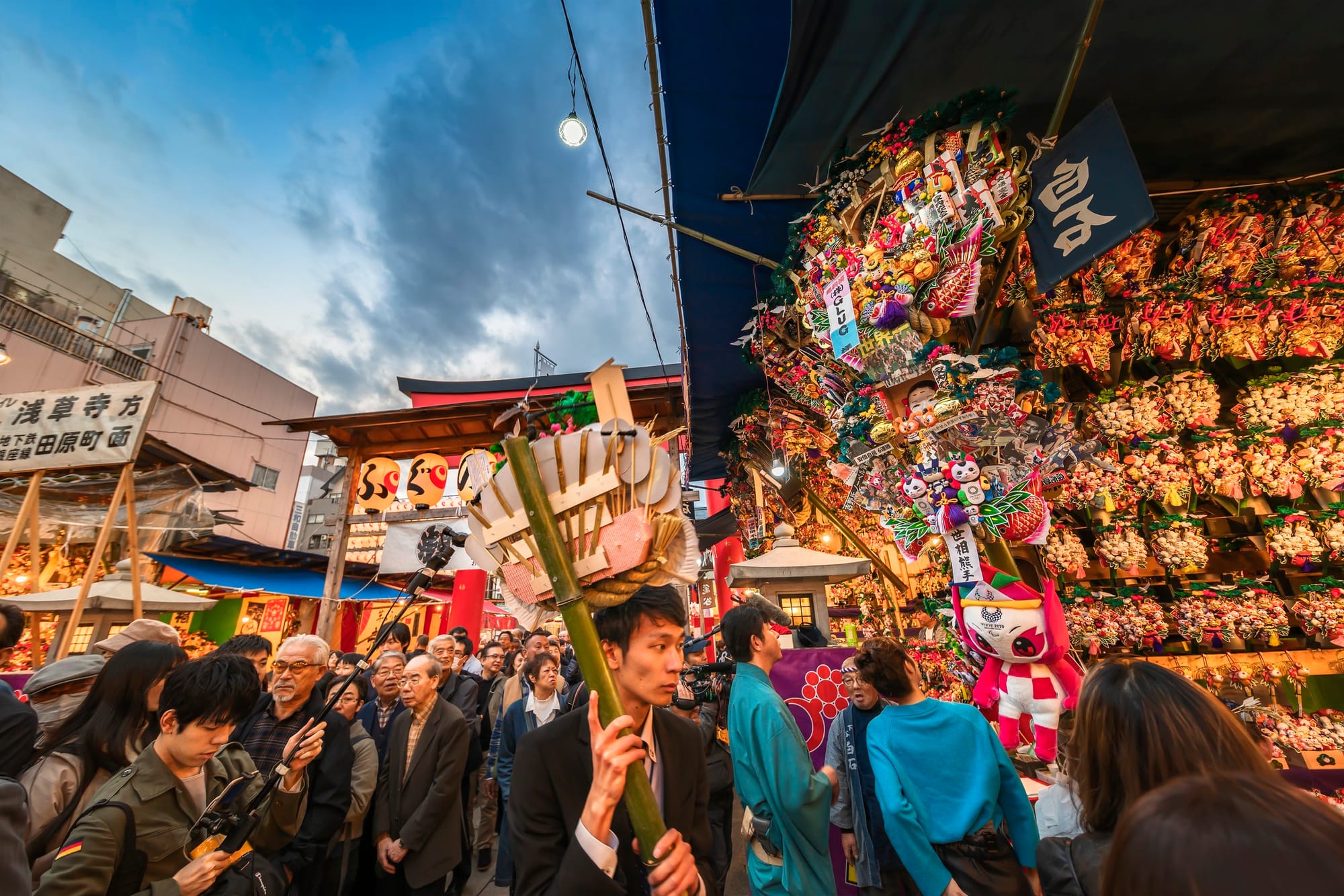 Visitantes frente a puestos de rastrillos decorados en la feria Tori-no-Ichi